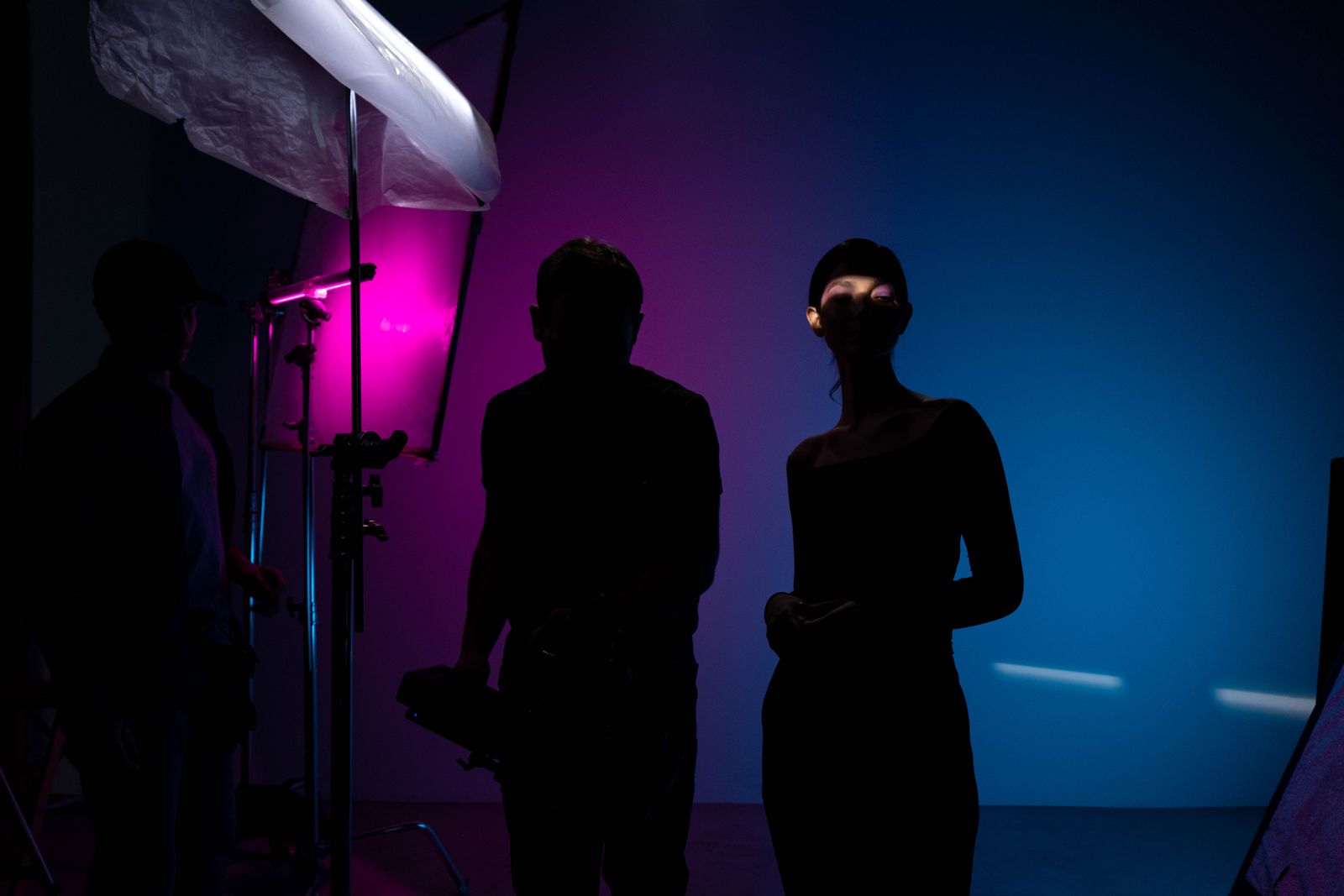 Two crew members in the studio lit by coloured lights